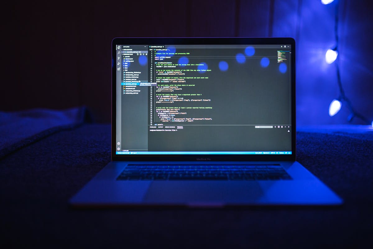 Laptop showing code in a dark room lit with blue light